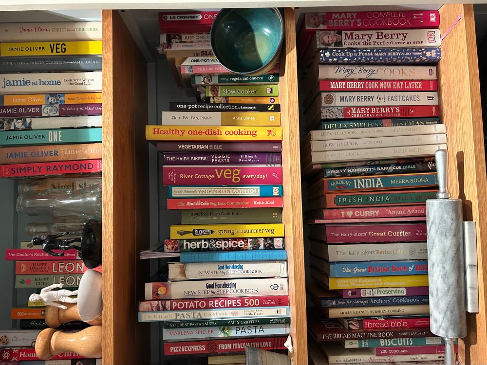 A bookshelf of cookery books with the image flipped ninety degrees so the books look as though they’re in three piles. I collect cookery books hoping one will come with a free chef  No luck so far 🤷‍♀️