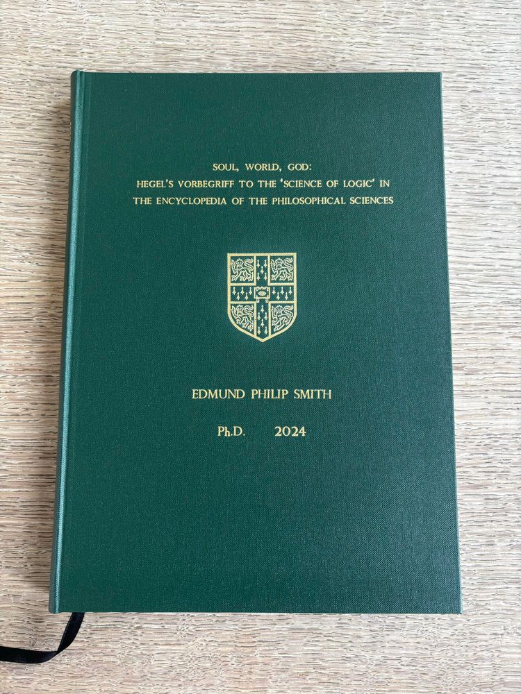 A green hardback book with gold text reading “Soul, World, God: Hegel’s Vorbegriff to the ‘Science of Logic’ in the Encyclopaedia of the Philosophical Sciences. Edmund Smith Ph.D. 2024.”