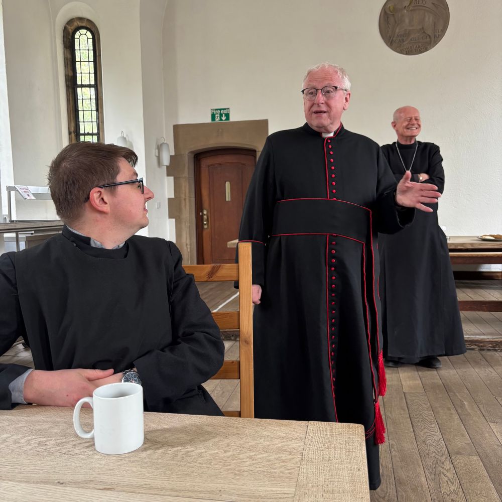 Three people laughing in cassocks.
