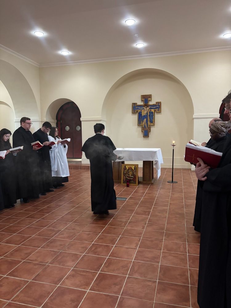 Some people in cassocks in a chapel.