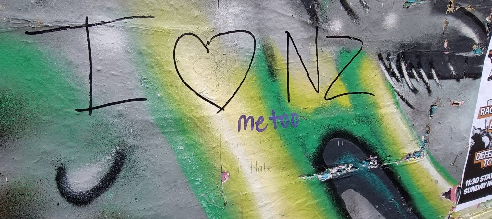 Writing saying "I ♥️ NZ" in black marker on spray painted artwork on a wall.

Below is written "me to" in a paint marker