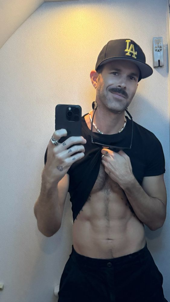 Kingofflop bored and taking airplane bathroom selfies. All black cargos and crop top pulled apart for a little flax of the abs on this thirsty Thursday. Black and gold LA hat because … GO DODGERS