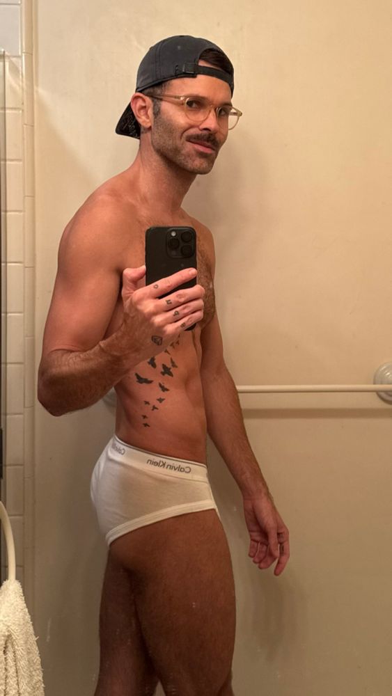 Kingofflop snapping a quick pic in his bathroom mirror wearing only his glasses a backward dodgers hat and white Calvin Klein briefs to say hello to the tighty whitey Tuesday bros