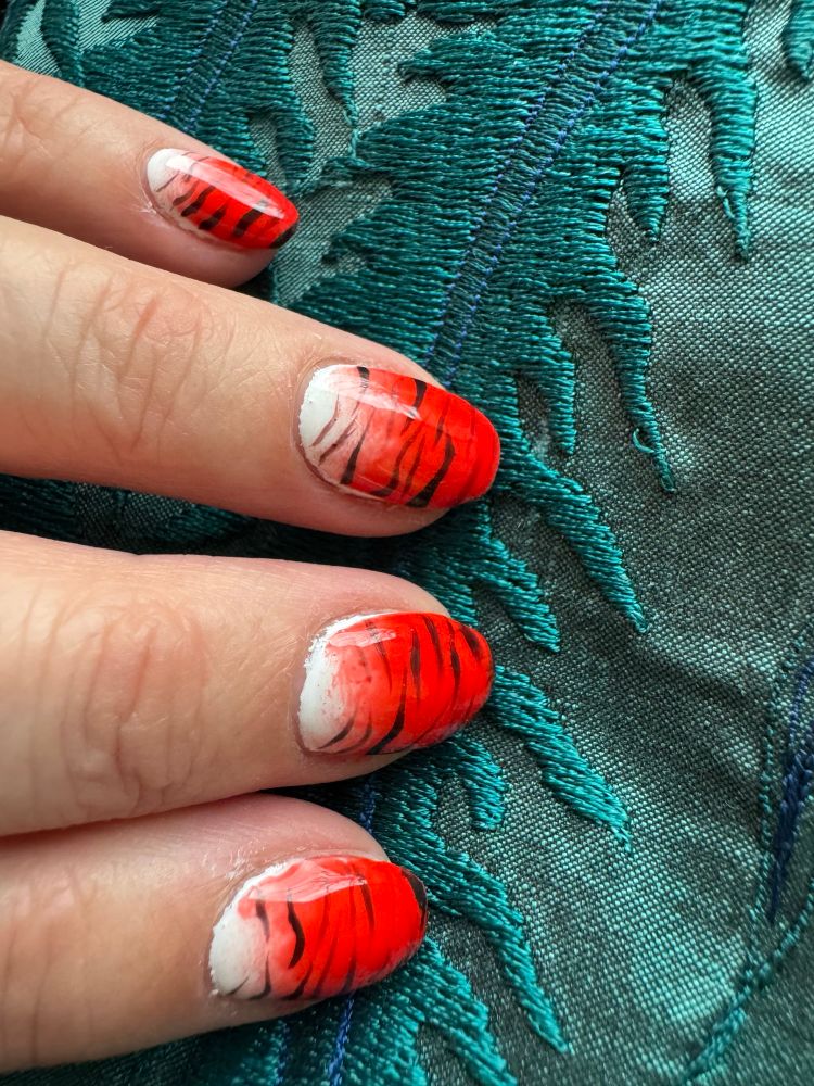 Fingernails painted to look like tiger fur.