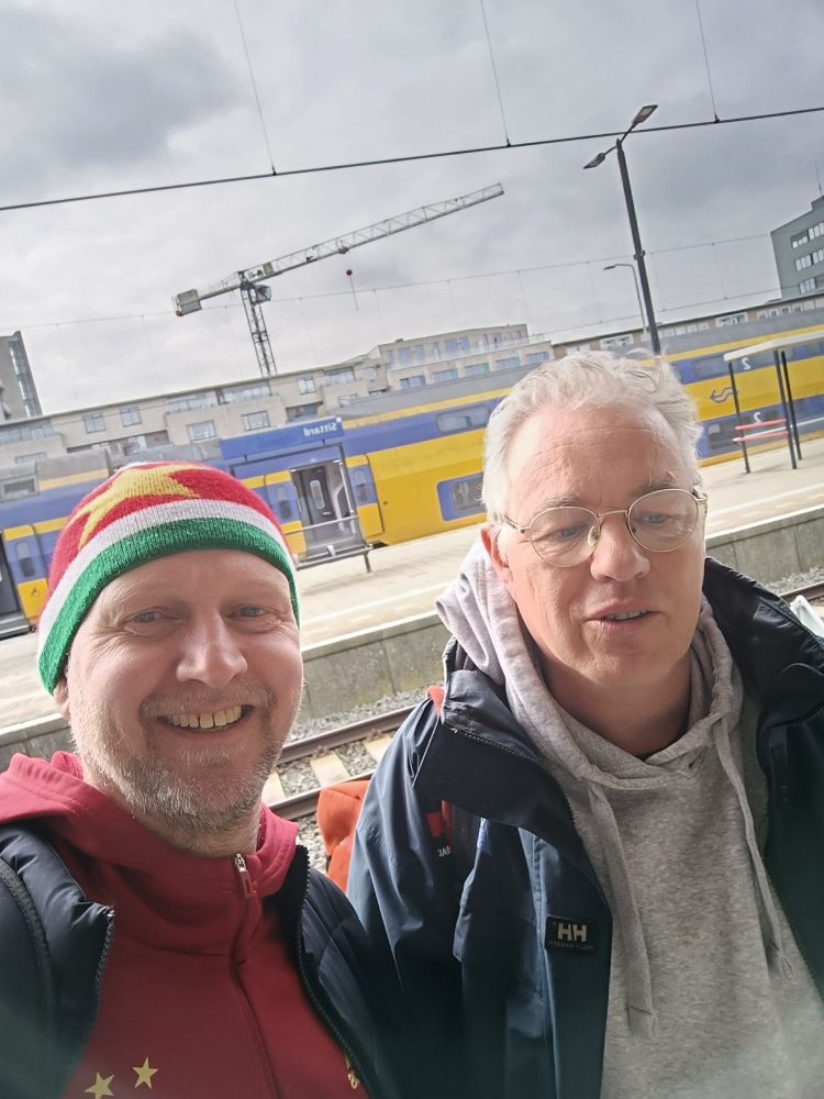 Twee vrolijke mannen van boven de vijftig op station Sittard. Surinaamse muts natuurlijk op.