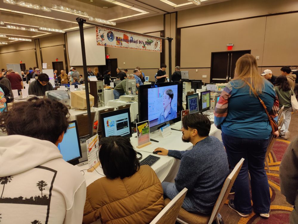 Several people gathered around computers to play edutainment games. 