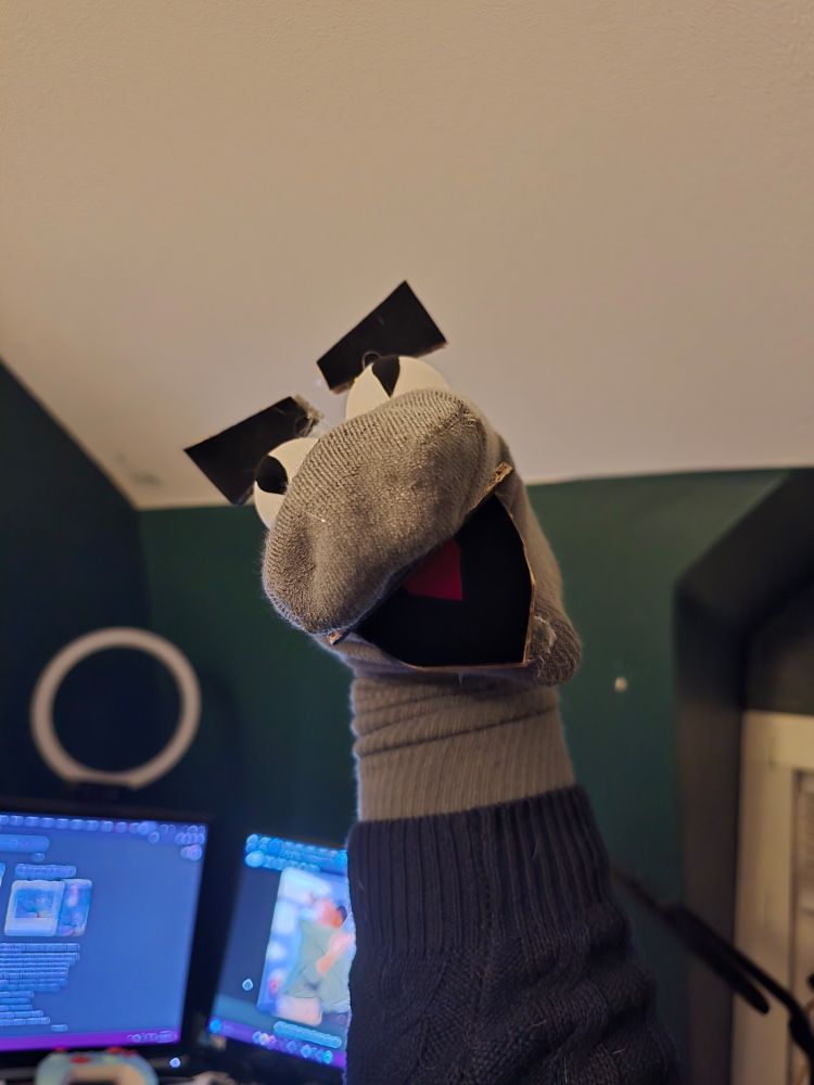 A Goofy and angry dinosaur sock puppet.