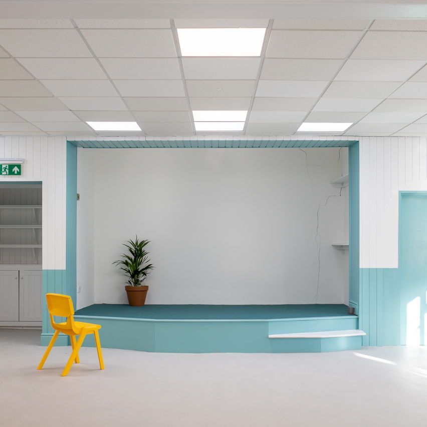 A large event room with a blue stage and panelling and white walls