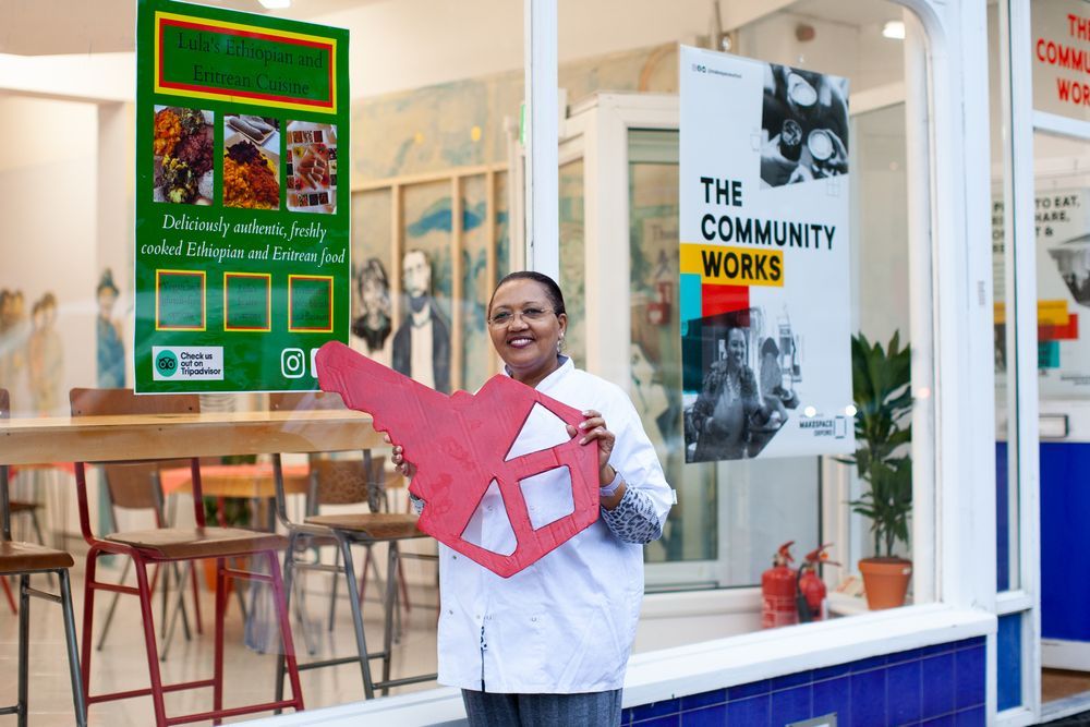 Lula standing outside The Community Works holding a giant red key