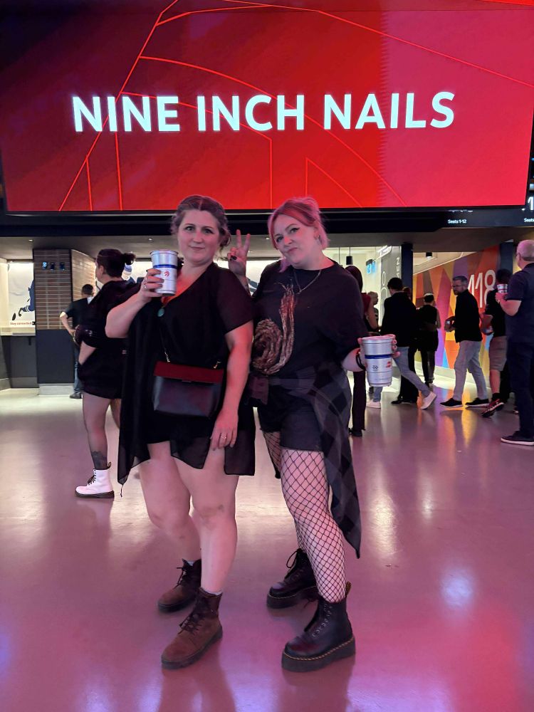 My bestie and I dressed in mandatory black with doc martens in front of a bright red Nine Inch Nails sign.