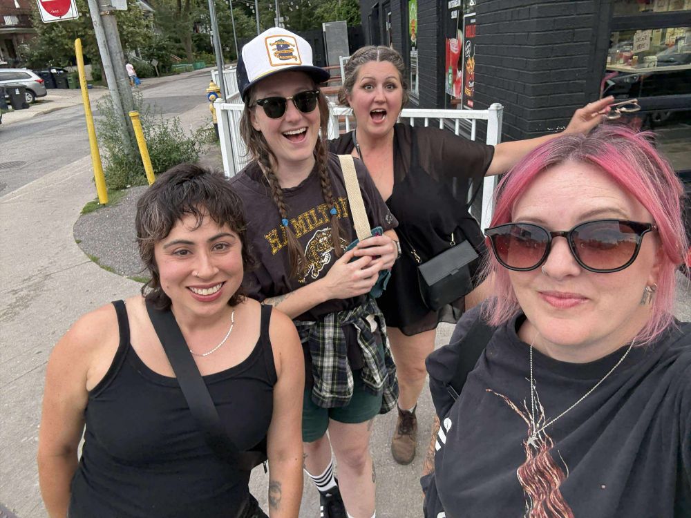 4 ladies in plaid, black, & black eyeliner on a Toronto side walk looking very excited.