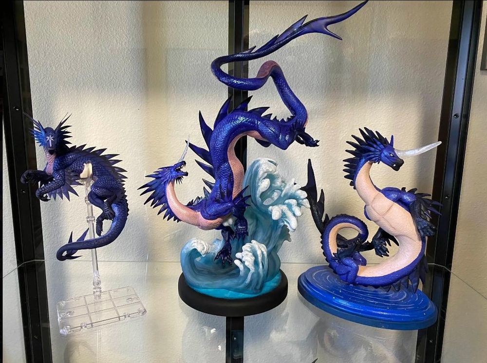 A photo of three blue noodle dragon statues in a glass display case.