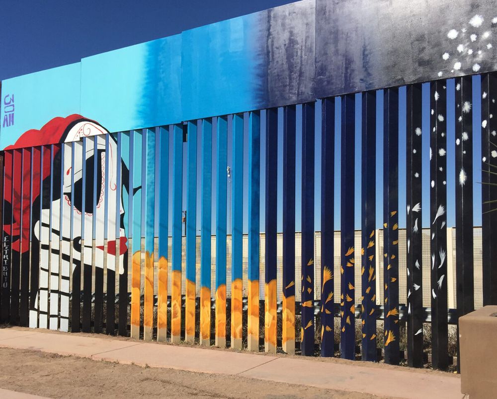 Colorful murals on the Mexico side of the US border fence.