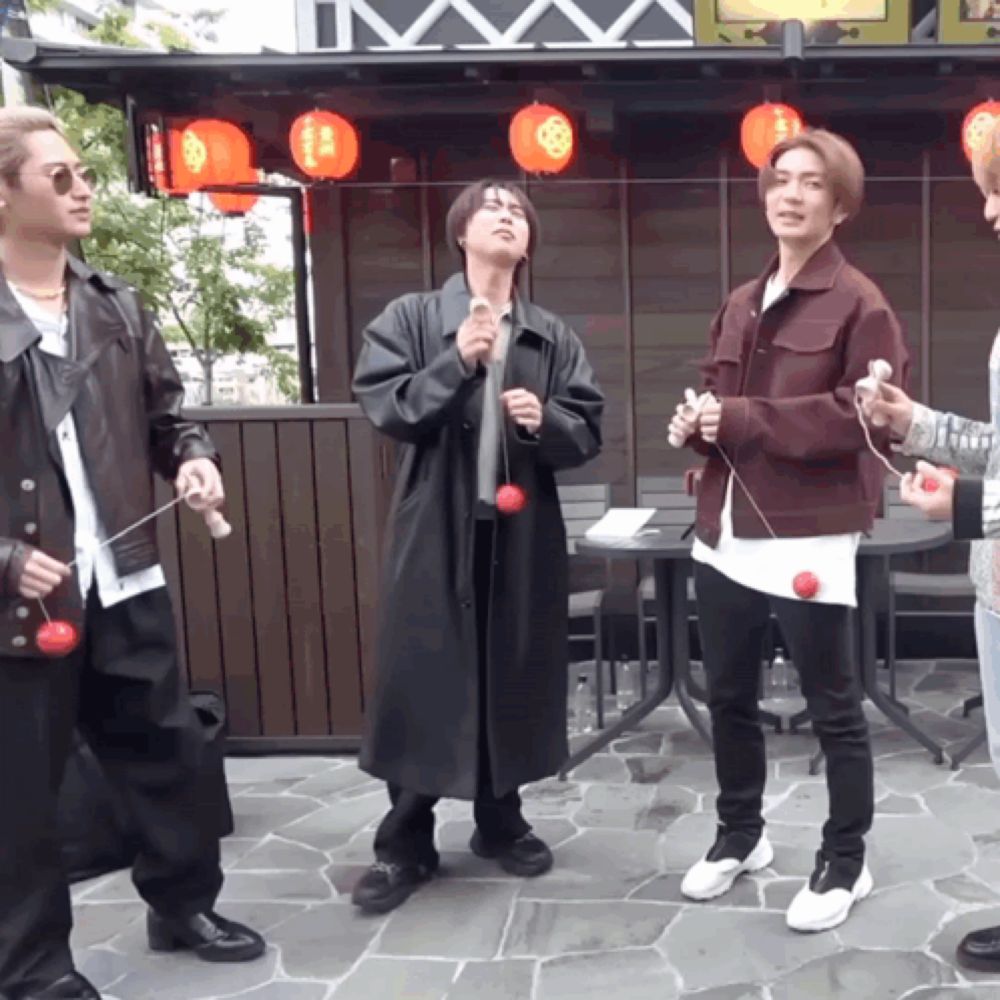 a group of young men are playing with red balls in front of a building with red lanterns