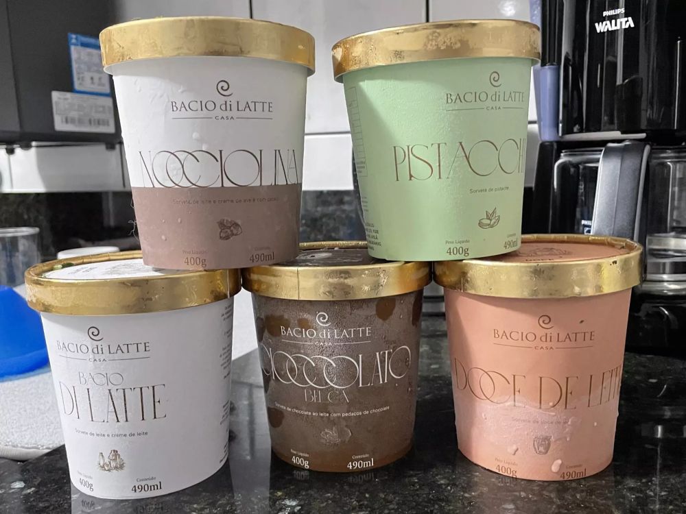 Foto de 5 sorvetes de diferentes sabores da marca Bacio di Latte em cima de uma pia de cozinha. 