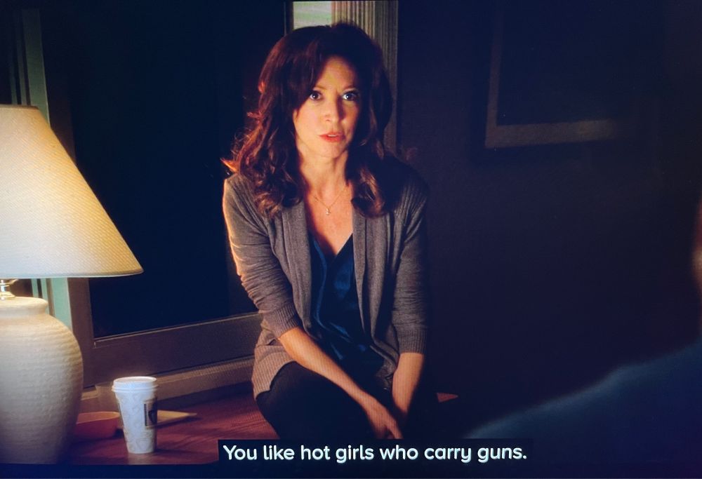 image of brunette woman sitting down and saying “You like hot girls who carry guns.”