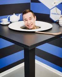 Kai Pflaume steckt seinen Kopf durch einen Tisch