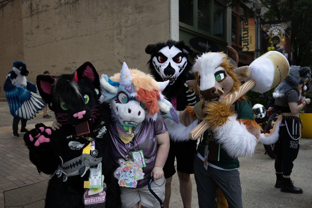 A photo of 4 fursuiters, Darkstar the demon cat, Parfait the dragon, Krak the wolf, and Blanc the bison in the streets of Pittsburgh. 
