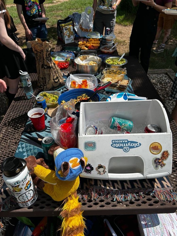 A picnic table full of various food and drinks. 