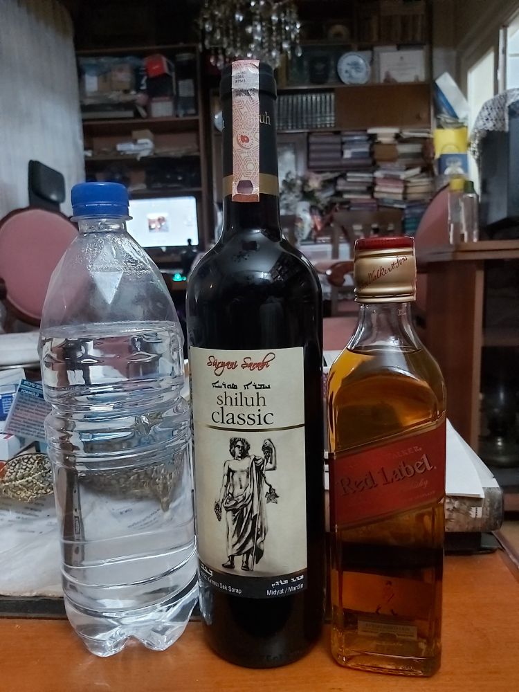 Three bottles of spirit. Left to right: Homemade Georgian Chacha; Assyrian red wine; Johnnie Walker Red Label whiskey.