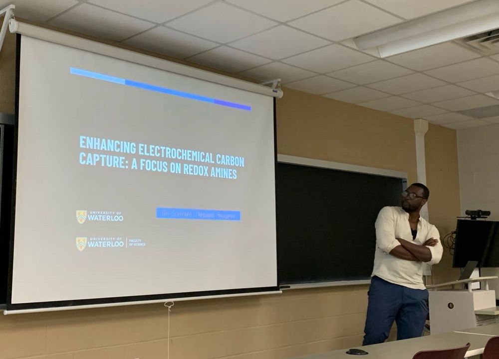 Conrard Tetsassi Feugmo presenting a slide with title “Enhancing Electrochemical Carbon Capture: A Focus on Redox Amines” at the Chemistry Department of UNB