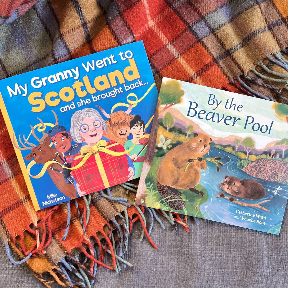 A photograph of the two books My Granny Went to Scotland and she brought back, and By the Beaver Pool, laying on top of a tartan blanket.