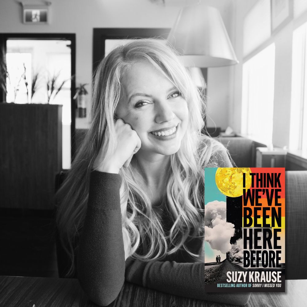 A black and white photo of writer Suzy Krause, who is a light skin-toned woman with long blonde hair. She sits in a booth of a restaurant and smiles at the camera. The cover of her book I Think We've Been Here Before is overlaid on the photo.