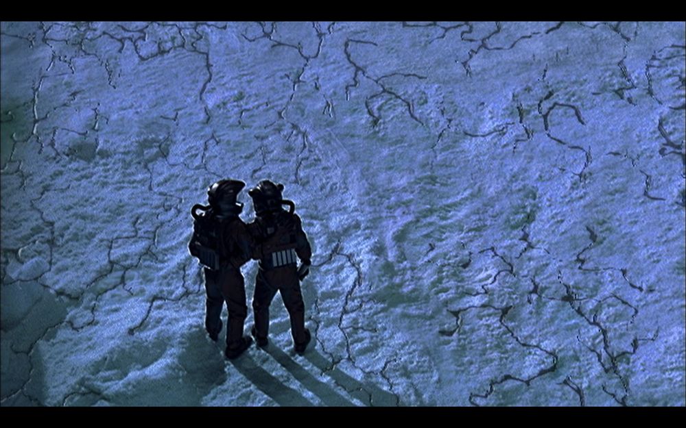 A wide shot of two humanois in protective suits standing on cracked ice.