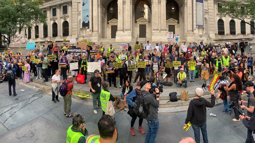 Activists bearing anti-Trump signs gather on the steps of the NY Public Library to discuss their plans for the day.