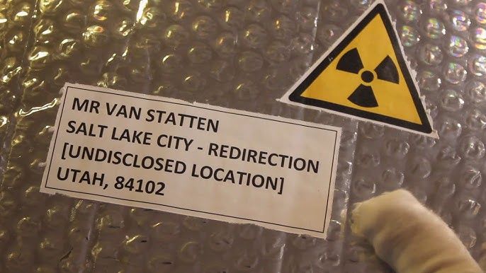 A package being held by a gloved hand with a radioactive symbol on it. It's addressed to,
"MR. VAN STATTEN
SALT LAKE CITY - REDIRECTIO
[UNDISCLOSED LOCATION]
UTAH, 84102"