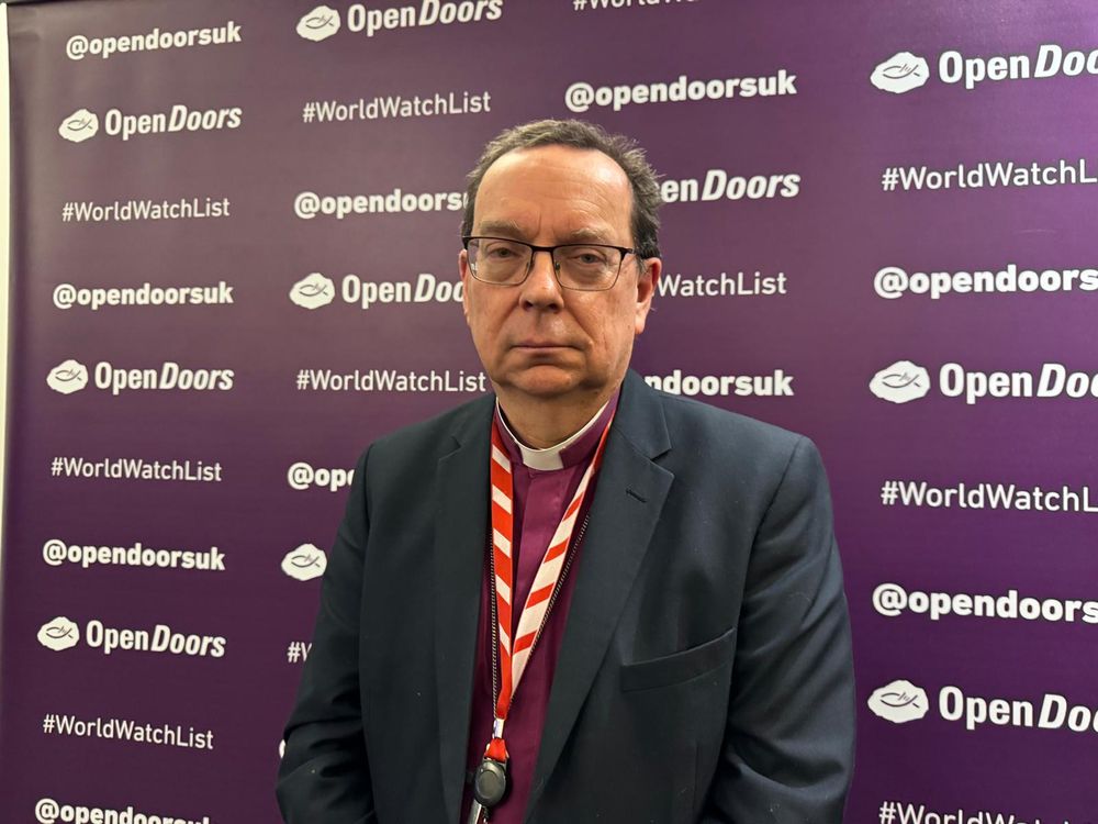 Philip Mounstephen, Bishop of Winchester, standing in front of a backdrop with the logos and hashtag #WorldWatchList of Open Doors UK. 