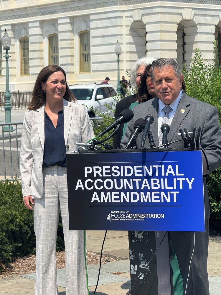 ECU President Tiffany Muller standing next to Rep. Joe Morelle on the left while he speaks behind a podium. Sign in front of podium is blue with white text that says “Presidential Accountability Amendment.” Below is smaller text that says “Committee on House Administration.”