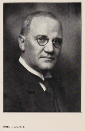 Sepia-toned photograph of a white man wearing glasses. He has a very high forehead/hairline. He is wearing a dark-coloured suit. Text at the bottom reads 'John MacNeill'.