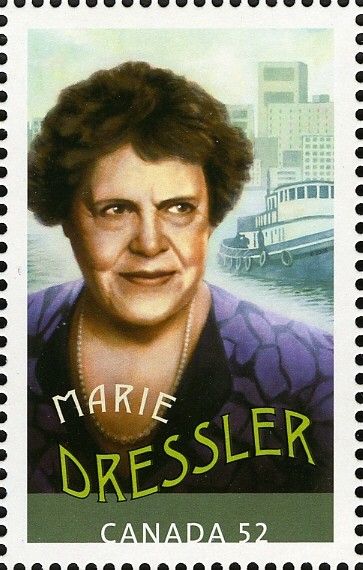 Canada Post stamp of Marie Dressler. She is a white woman with short red-brown hair and is looking into the distance behind our right shoulder. She wears a purple patterned top and a string of pearsls. There is a tugboat in the background.