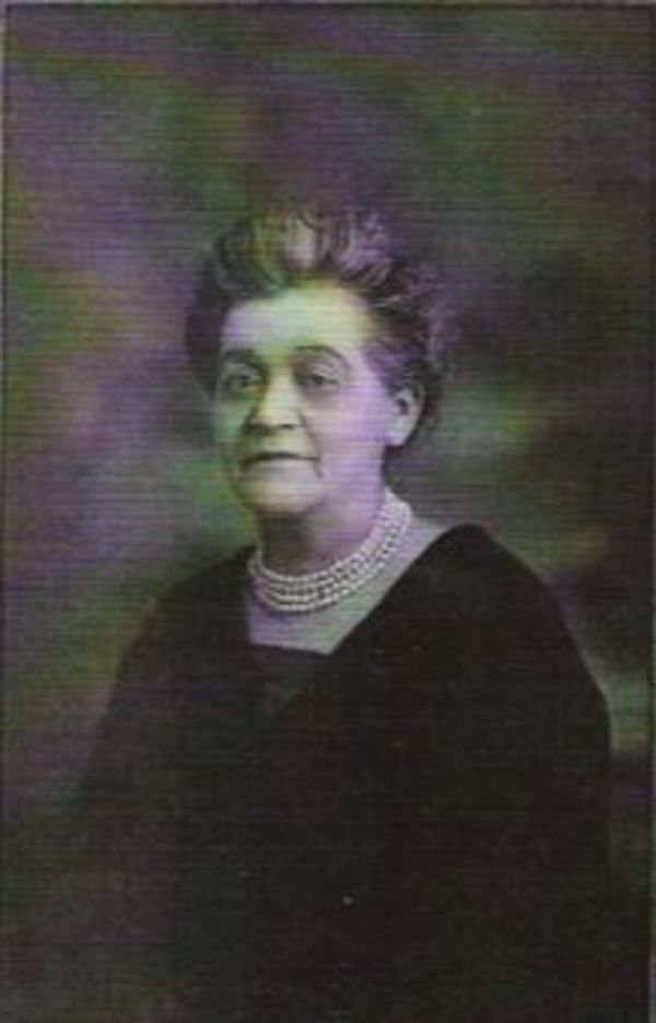 A woman in a dark outfit wearing a multi-stranded necklace.