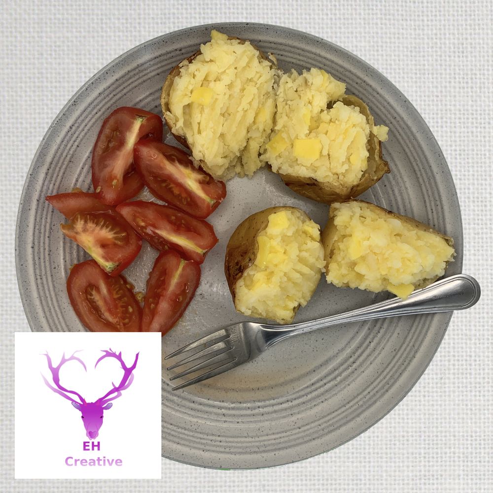A plate of cheese stuffed baked potatoes, with tomatoes and a folk