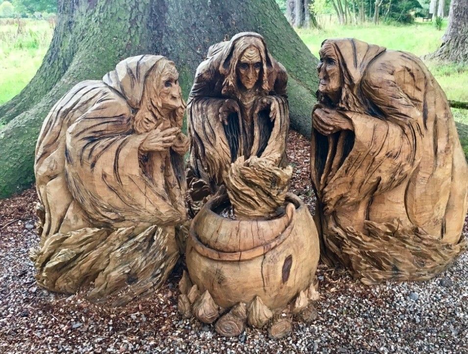 Wooden carving of three witches hunched over a cauldron