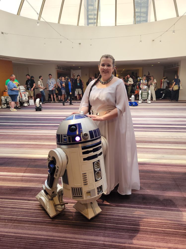 Sarah dressed as throne ceremony Leia, posing with R2D2