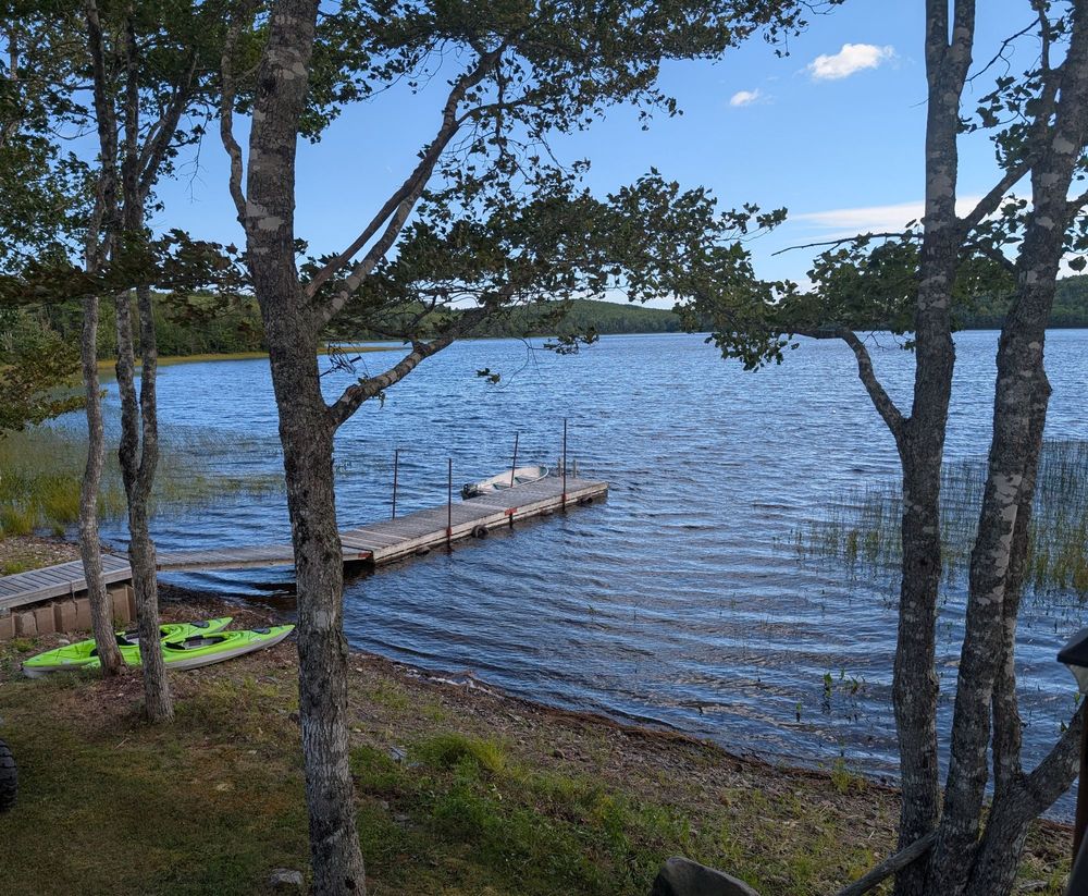 A dock extending into a rippling lake. A couple kayaks are sitting next to the dock
