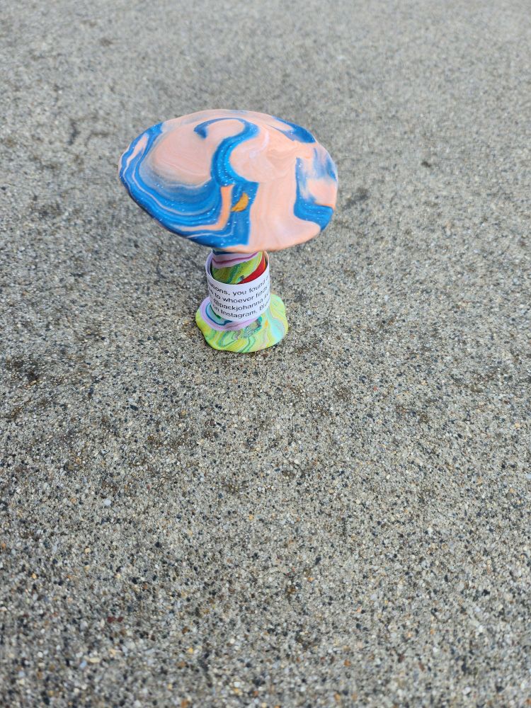 Polymer clay mushroom with rainbow base and pink and blue swirled top. The center swirl appears to be almost a question mark.