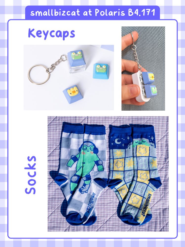 Text: smallbizcat at Polaris B4.171, Keycaps, Socks.
The photographs show 3 different keycaps, one of a frog face in blue, the other in purple and one of a yellow duck on purple. They can be purchased alone or on keychains with one or two slots.
Below is a picture of two pairs of socks, one showing a rollerskating frog with headphones, the other a frog under a big cozy patchwork blanket. 