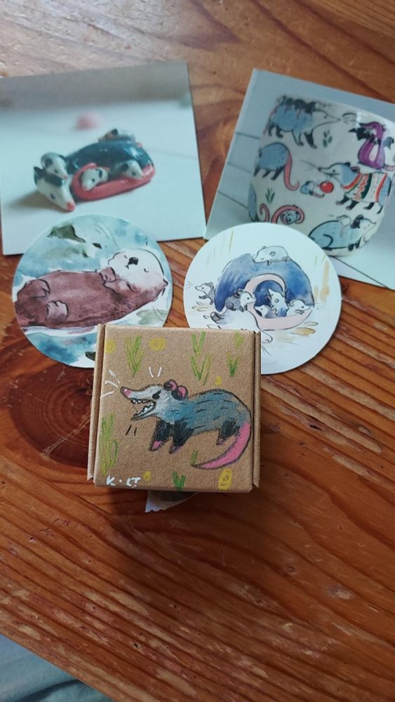 Small box with art of a yelling possum, and stickers and prints behind it.