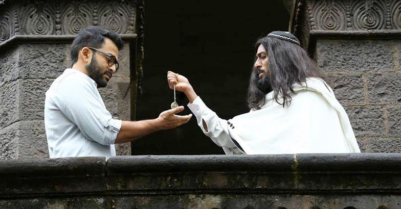 a man wearing a kippah and a shawl hands a piece of jewellery to another man. from the film Ezra / എസ്ര (2017) 