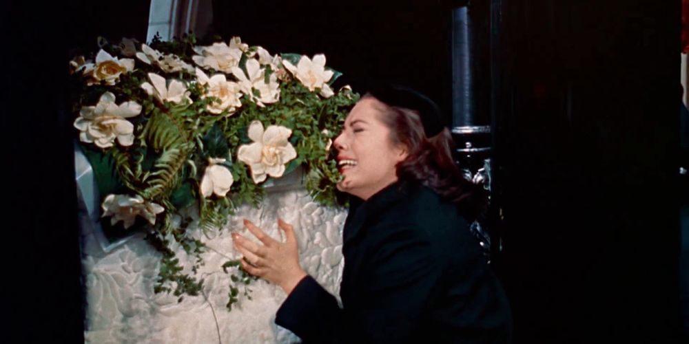 a young woman (Susan Kohner) clutches a casket adorned with flowers, crying. from Douglas Sirk's Imitation of Life (1959)