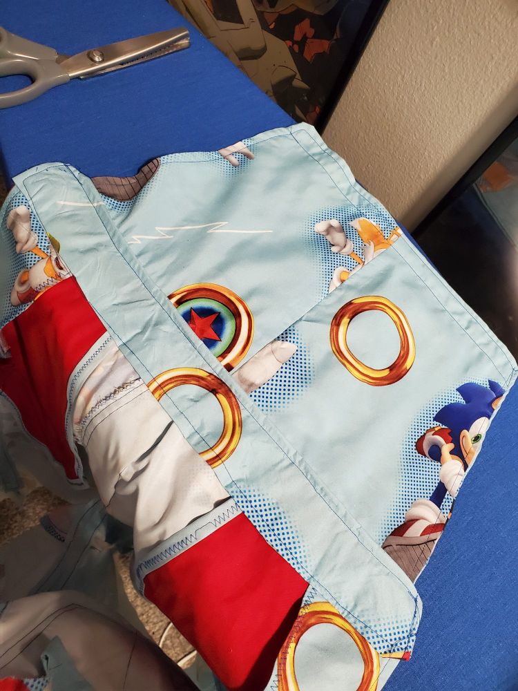 The inside of the top half of a jumper made of sonic bedsheets laid out on an ironing board