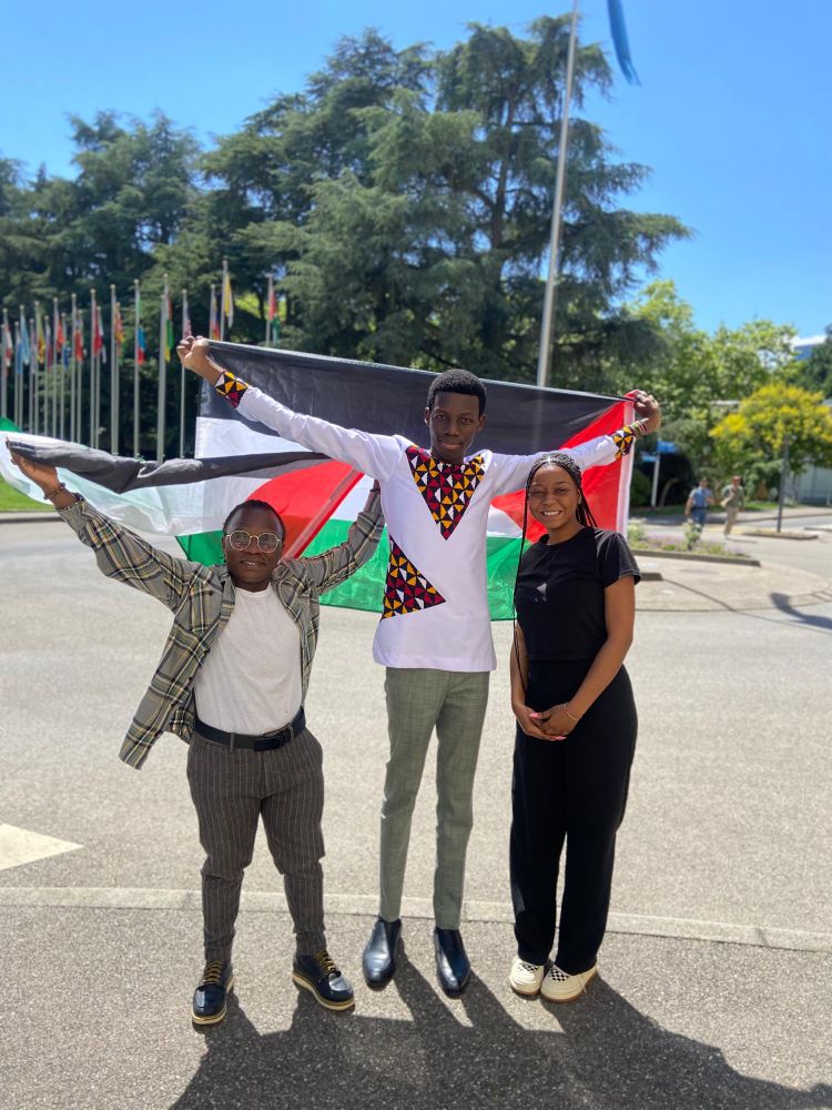 Three young advocates: Andy Maxwell and Kerry Mwita carrying Kenyan flags. Leila is next to them in a black outfit smiling to the camera 