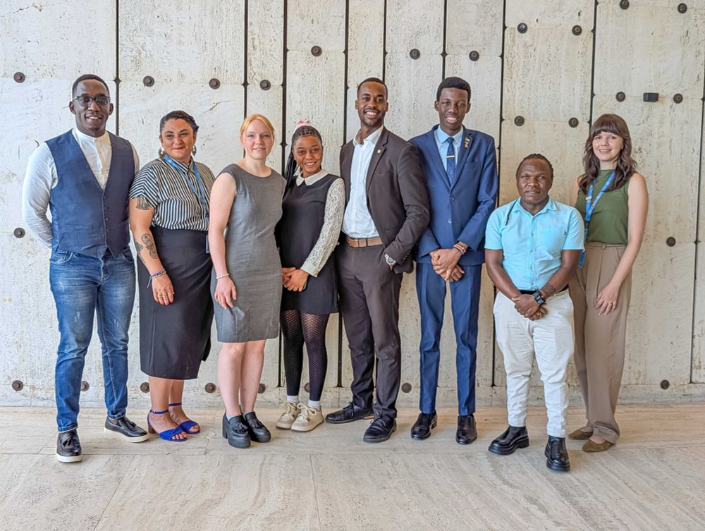 A group of 8 people consisting on Women Deliver staff, Emerging Leaders, and partners at HRC59. They use formal attire, standing next to each other and smiling to the camera. 
