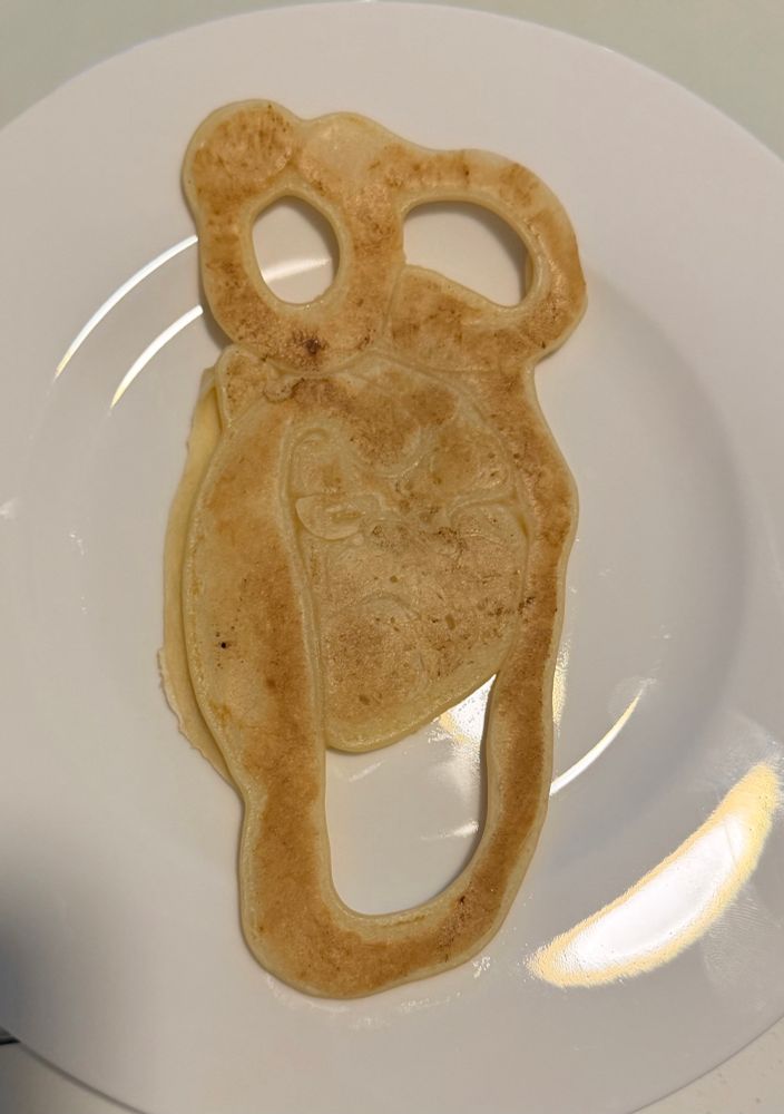 Ein länglicher Pfannkuchen- Eierkuchen, der oben zwei Löcher hat, die Augen sein könnten, und unten rund zuläuft. Auch unten ist noch ein mundförmiges Loch.