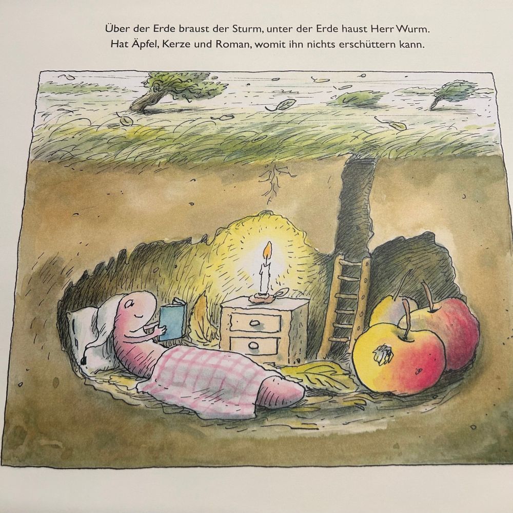Ein Kinderbuch Bild, Herr Wurm liegt eingekuschelt mit einem Buch bei Kerzenschein und liest, als Proviant hat er zwei Äpfel. Darüber steht zu lesen: Über der Erde braust der Sturm, unter der Erde haust Herr Wurm.
Hat Äpfel, Kerze und Roman, womit ihn nichts erschüttern kann.