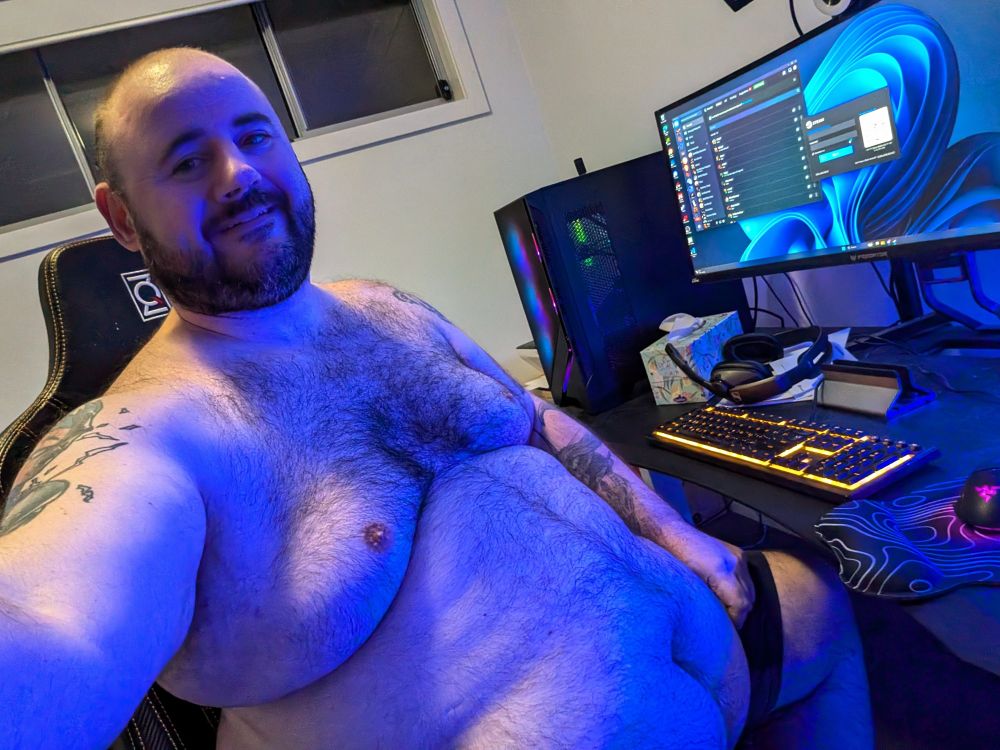 Large hairy nerd sitting at the computer under blue lights